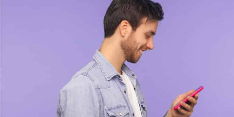 homem olhando para o celular acessando o aplicativo do banco Cora