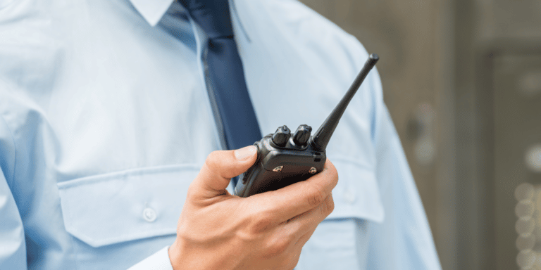 Profissional trabalhando como guarda e passando recado no rádio. Saiba como atrair cliente para empresa de segurança.