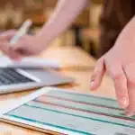 Pessoa faz anotações enquanto checa informações em um tablet, em imagem que ilustra artigo sobre Orçamento contínuo, também chamado de rolling forecast.