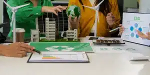 Pessoas conversam ao redor de uma maquete sobre ESG e sustentabilidade, em imagem que ilustra artigo sobre pequenas empresas