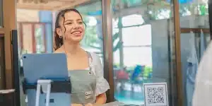 Mulher sorri ao atender um cliente, em imagem que ilustra artigo sobre recebimento em Pix para empresas