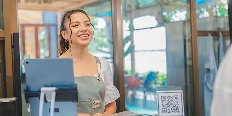 Mulher sorri ao atender um cliente, em imagem que ilustra artigo sobre recebimento em Pix para empresas